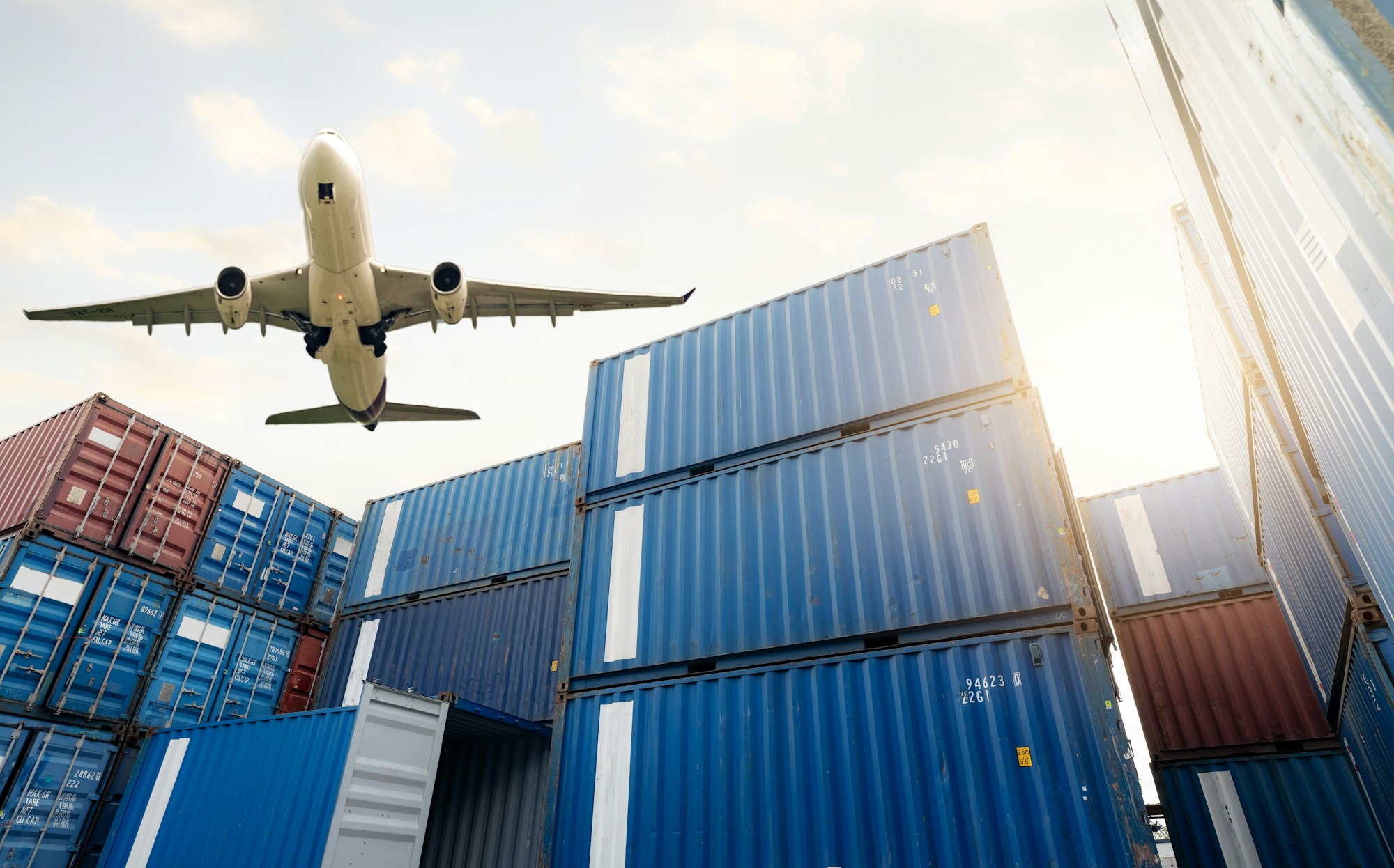 Air logistics. Cargo airplane flying above stack of logistic container. Cargo and shipping business.